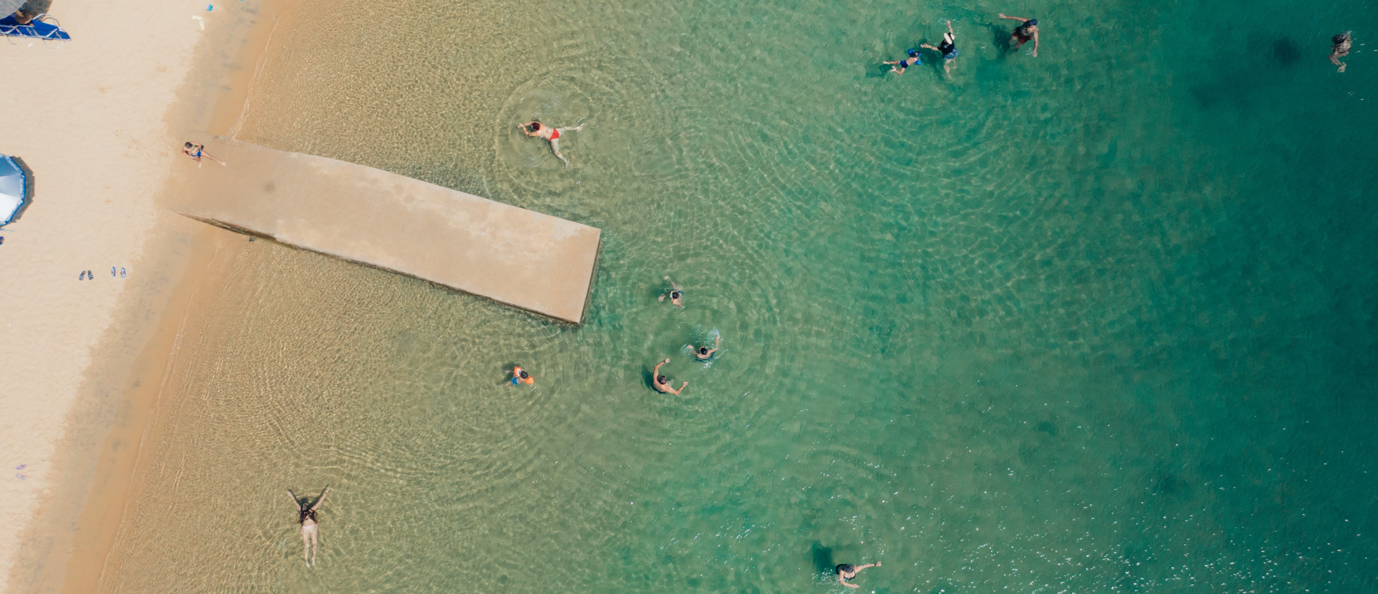 Childern swimming in turquoise waters around a dock