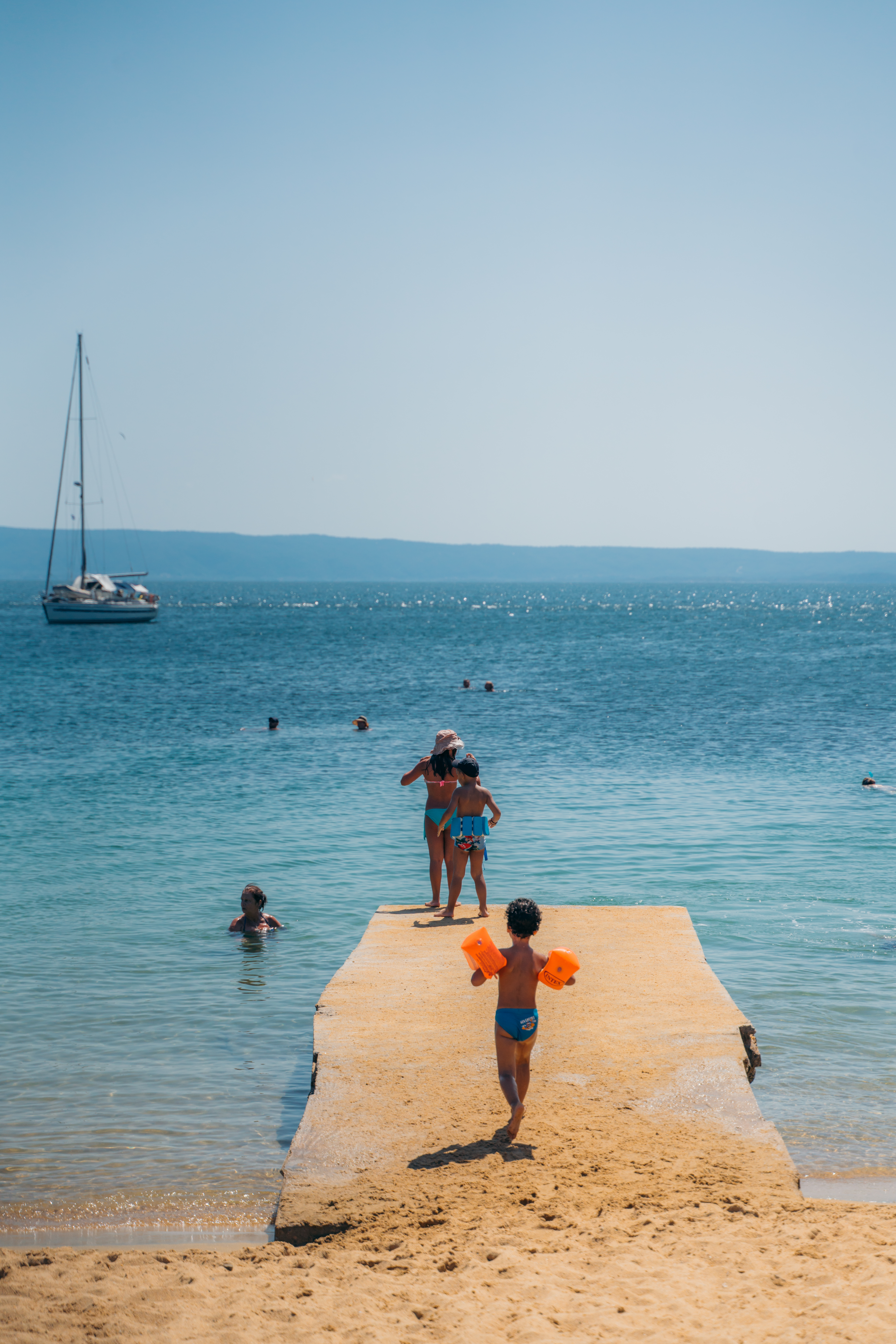 Children ready to jump into the sea from the dock