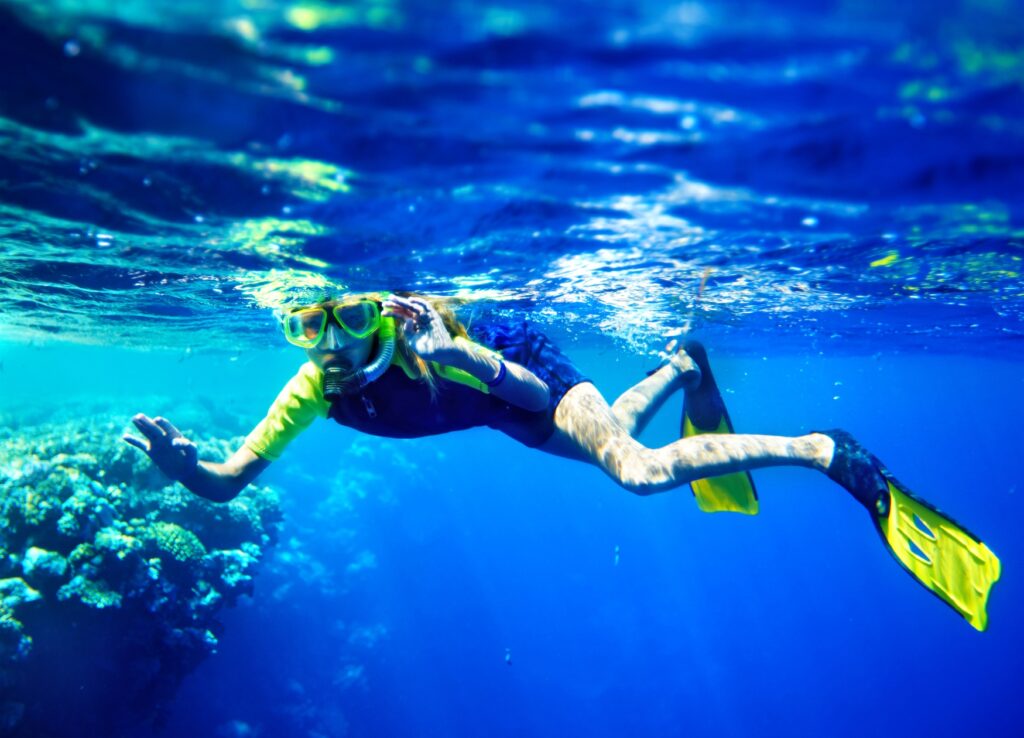 A child with a mask underwater, snorkelling
